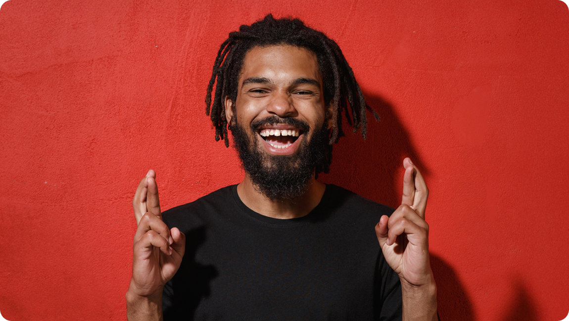 Smiling man with crossed fingers in front of a red background for the CP&KRELL May 2026 newsletter